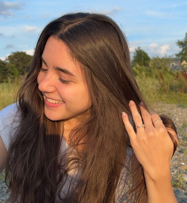 Maddy smiling by the water in warm evening light